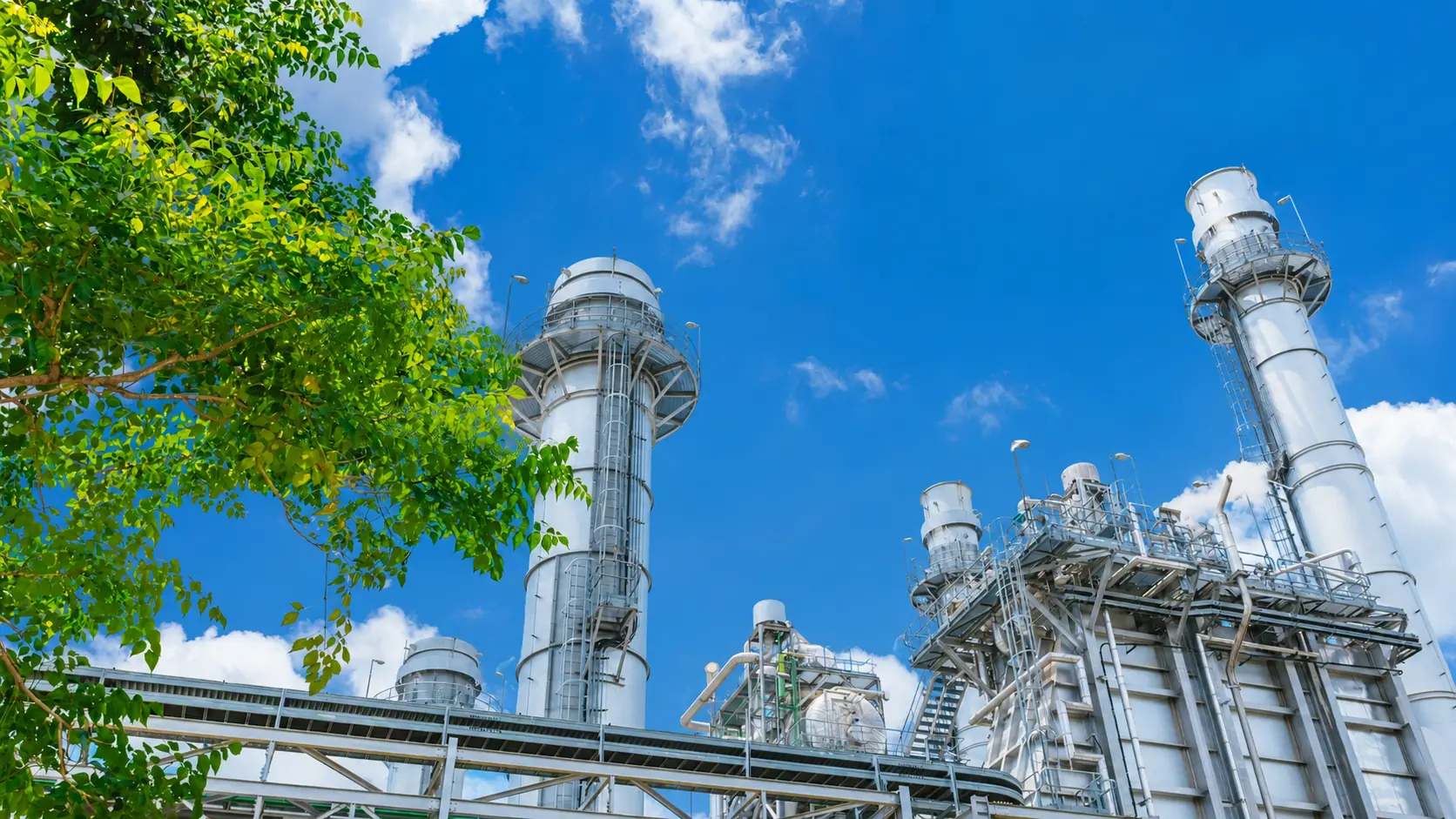 Industrial plant with insulated flue-gas ducting and stack under a clear sky